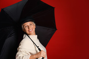 Beautiful mature woman with umbrella on red background