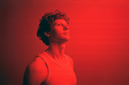 Pensive young man looking away in red light room