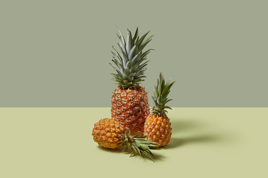 Three fresh tropical pineapples placed over duotone background