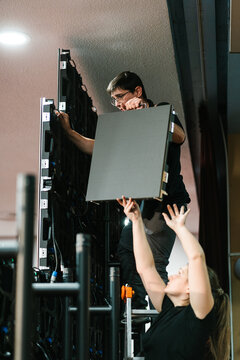 Young man giving video wall panel to woman coworker