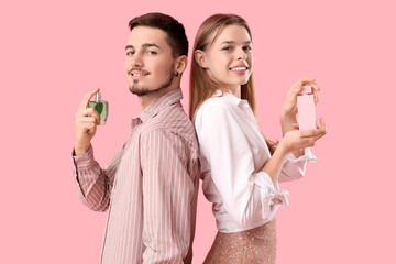 Young couple with bottles of perfume on pink background