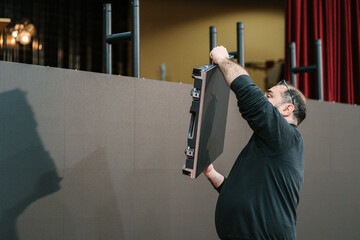 Male technician lifting video wall during indoor installation
