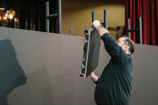 Male technician lifting video wall during indoor installation