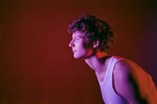 Curly hair man studio neon closeup. Looking forward face