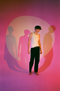 Young male posing in neon light on pink background