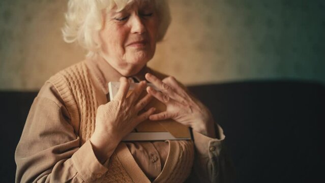 Upset old woman looking at family photo and crying, missing husband, solitude