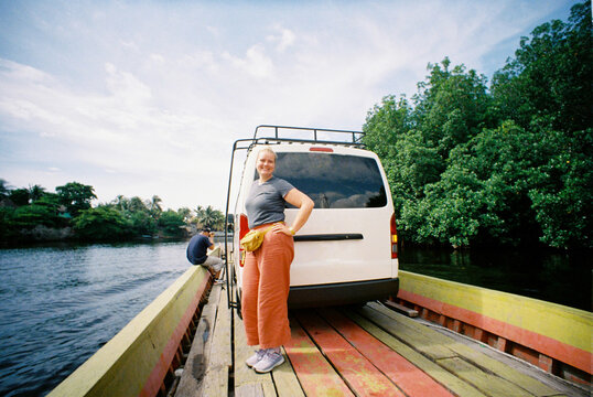 Woman standing on a wooden boat carrying a minibus