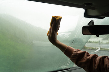 Woman cleaning window of the car 