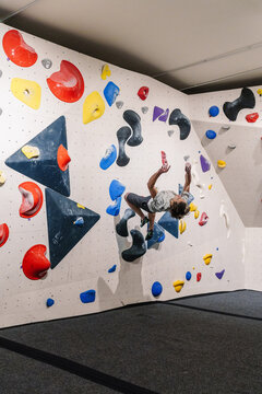 Skilled climber doing a backflip while training indoor climbing