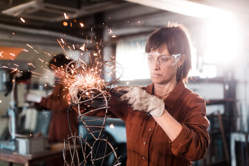 Metal sculptor using angle grinder at workshop