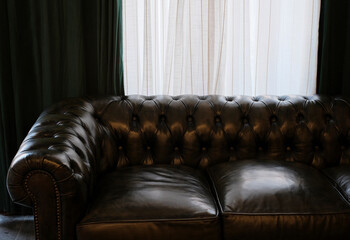 Closeup of leather sofa in front of curtains at home