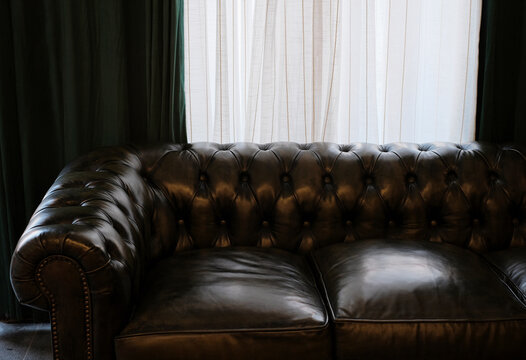 Closeup of leather sofa in front of curtains at home