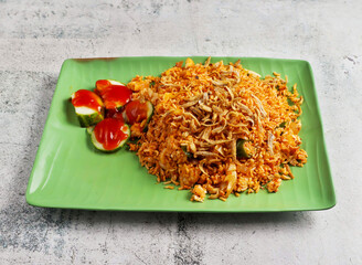 nasi goreng ikan bilis with fried onion and cucumber served in dish isolated on grey background side view of singapore food