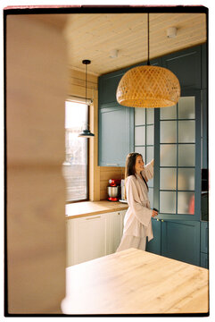 Happy woman decluttering in her modern cozy kitchen on a sunny day