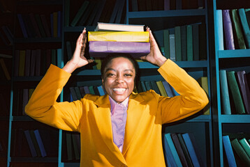 Smiling black woman with stack of books on head