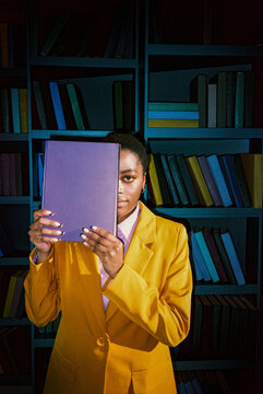 Woman hiding half of face behind book 