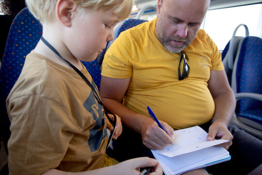 man with son playing some game on the notebook sitting on the train