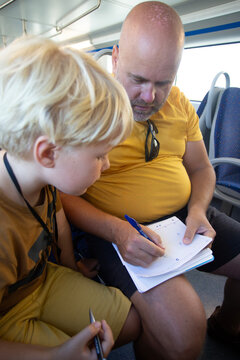 man with son playing some game on the notebook sitting on the train