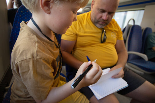 man with son playing some game on the notebook sitting on the train