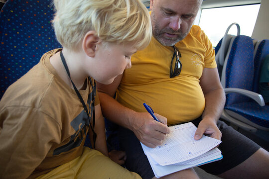 man with son playing some game on the notebook sitting on the train