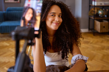 A young content creator is filming beauty videos in her living room.