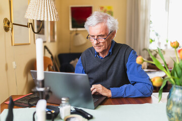 Senior man with white hair working on computer at home