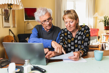 Senior citizen sitting at home paying family bills together