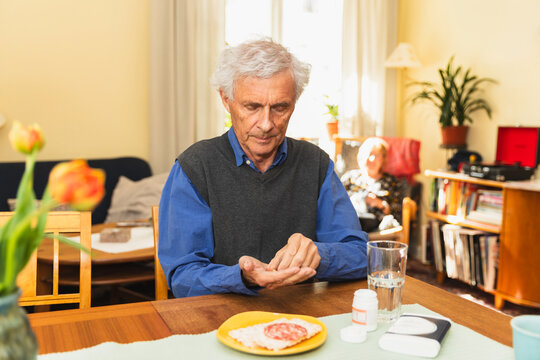 Focused senior man taking pills at home