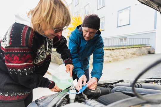 Senior couple putting water in coolant tank