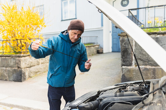 Active senior man checking engine oil