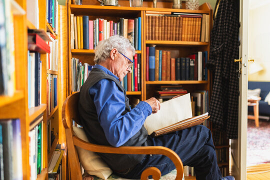 Senior retired man reading a book sitting in easy chair