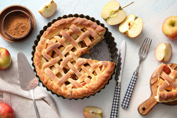 Tasty homemade apple pie with fruits, cinnamon and cutlery on light blue background