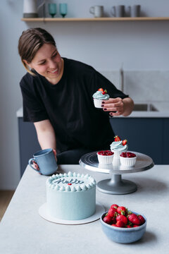 Woman Decorating Cupcakes in Kitchen