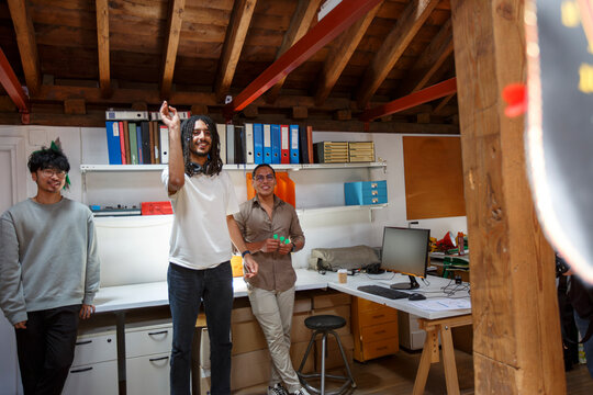 Group of coworkers playing darts in small office