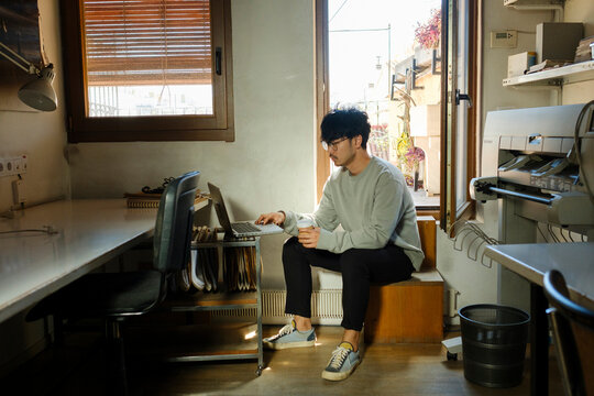 Young startup entrepreneur in messy office with laptop 