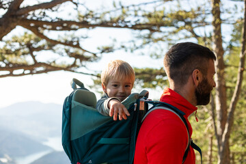 Portrait of a blond boy in a backpack carrier