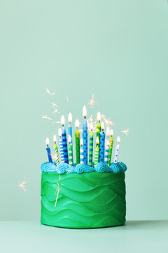 Green celebration birthday cake with lots of birthday candles