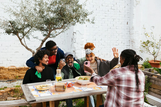 Diverse friends gathering together at table in community garden