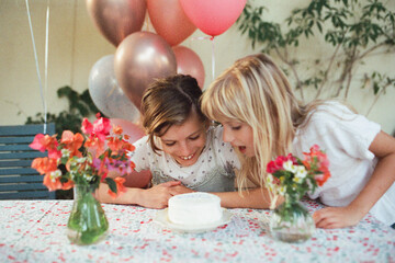 A girl wants to bite off a piece of a small creamy cake