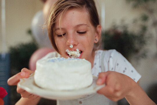 A girl eating a small creamy cake
