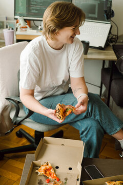 Young woman  takes a slice of pizza from a cardboard box 