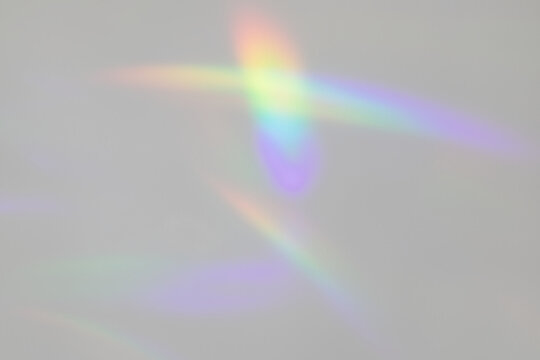 A photograph of abstract rainbow light patterns cast on a plain background.