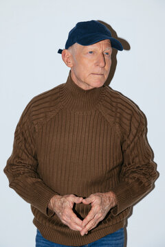 Senior man in baseball cap looking away in studio
