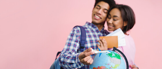 Happy teen couple preparing for trip with globe, girl holding passport and tickets on pink background