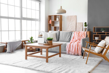 Modern interior of living room with cozy sofa, armchair and coffee table