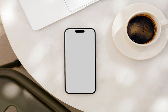 Mockup a phone with a white screen in in the morning cafe