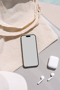 Mockup phone with white screen  on a sun lounger by the pool