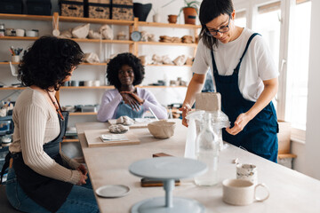 Obraz premium Tutor opening clay form plastic bag on class with diverse attendees.