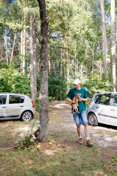 Man Carrying Puppy in Forest Parking Area