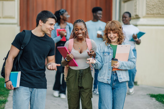 Diverse students near university building entrance walking towards camera